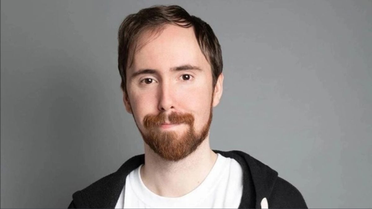 Asmongold Fights For His Life Explaining To Audience Why Taco Bell Is An "Ideal First Date" Asmongold-with-a-short-hair-style-smiling-against-a-greay-backdrop